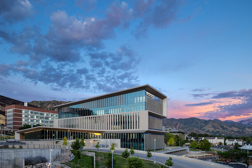 The Spencer Fox Eccles School of Medicine building at dusk, with the Wasatch Range in the background